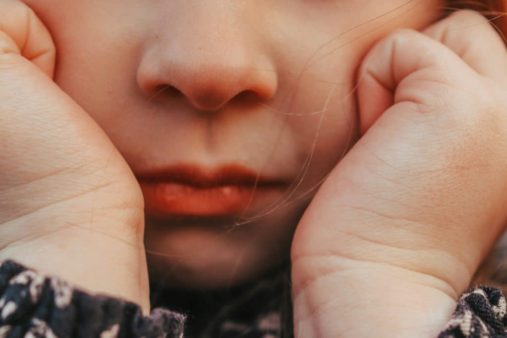 a close up of a person holding their hands to their face
